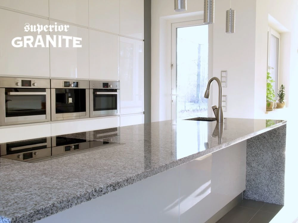 Modern white kitchen with polished stone island, showcasing custom granite countertops cost considerations for stylish and durable home upgrades.