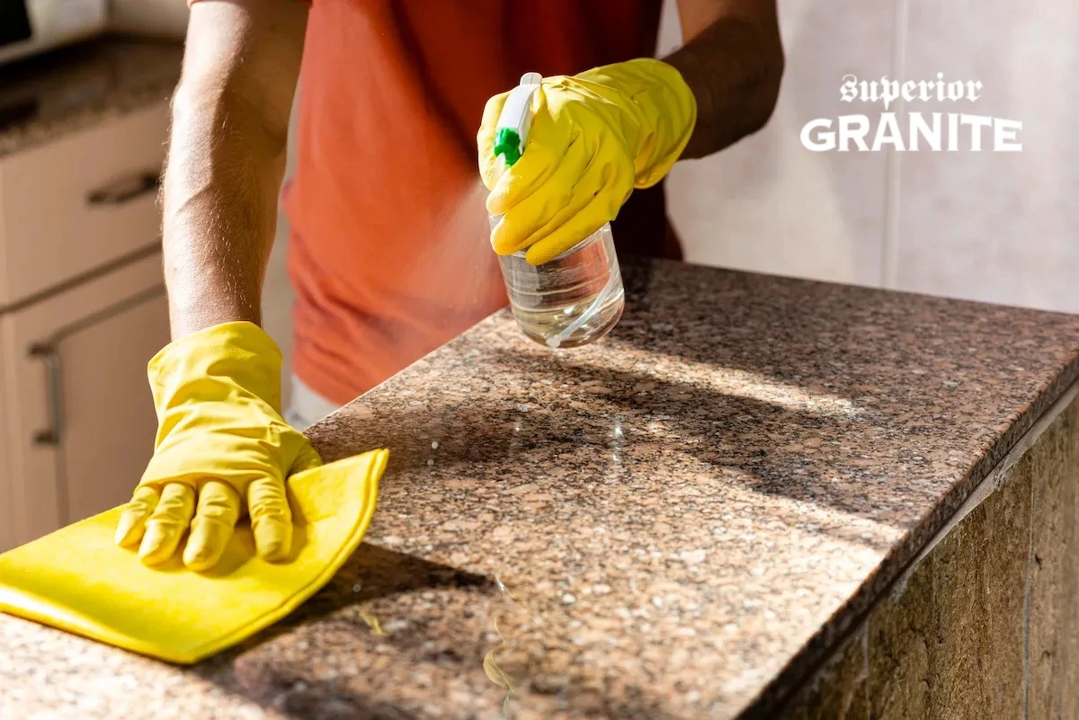 Professional using granite countertop stain removal spray to clean and restore a stone kitchen surface.