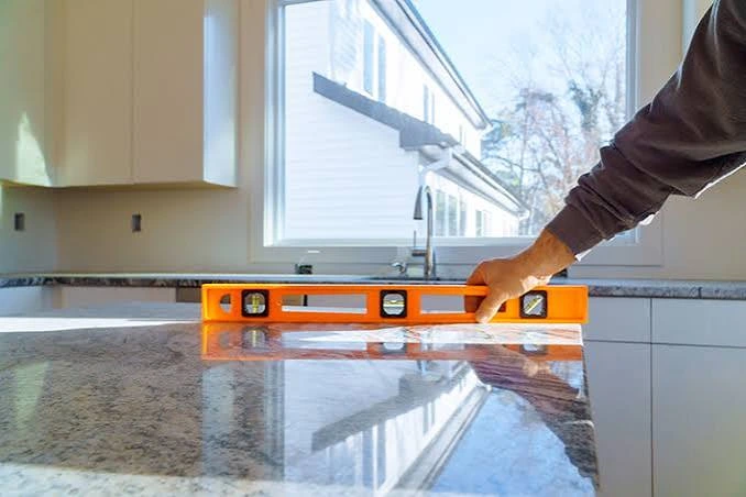 Contractor checking leveling during a granite countertop installation.