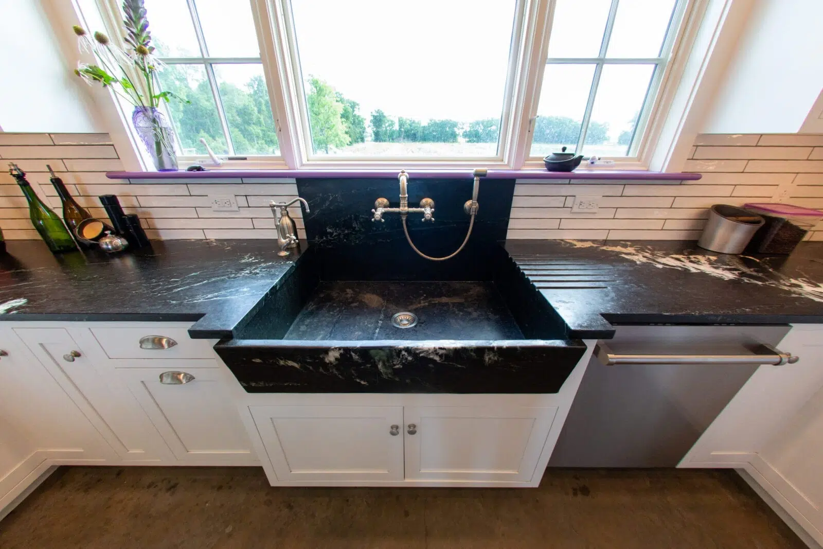 Black marble farmhouse kitchen basin integrated into custom stone sinks setup.