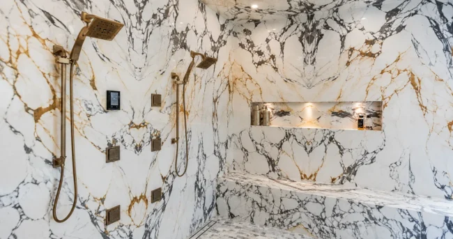 Marble-look large slab walk-in enclosure with gold fixtures: Porcelain Custom Showers. Marble-look large slab walk-in enclosure with gold fixtures: Porcelain Custom Showers.