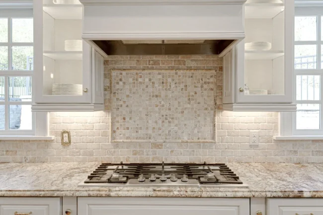 Natural stone surface with gas cooktop and mosaic backsplash for limestone countertops.