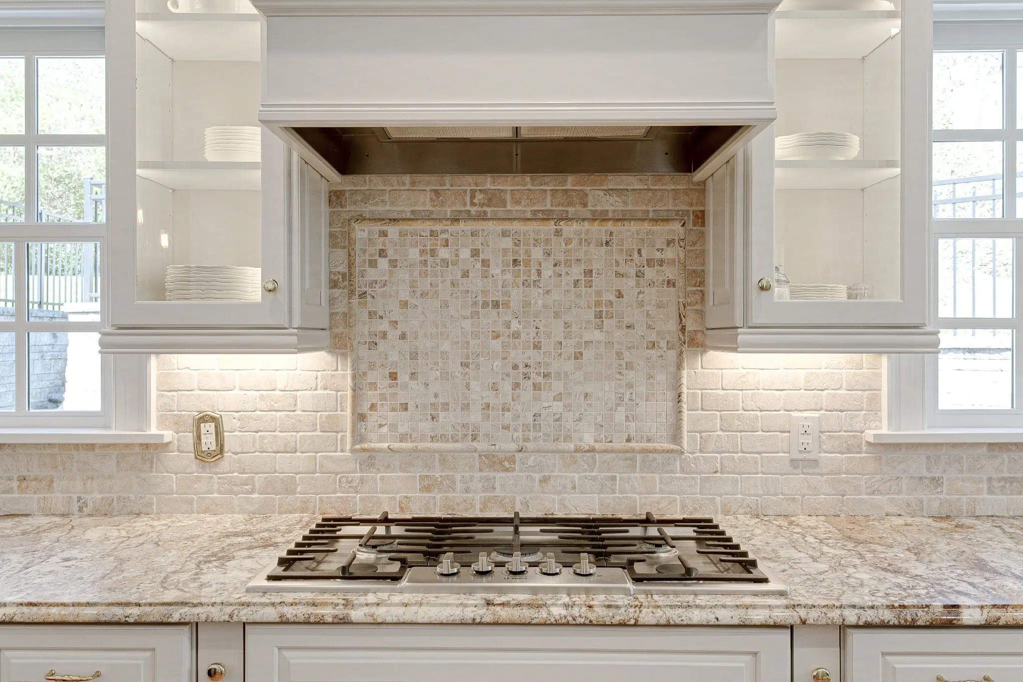 Natural stone surface with gas cooktop and mosaic backsplash for limestone countertops.
