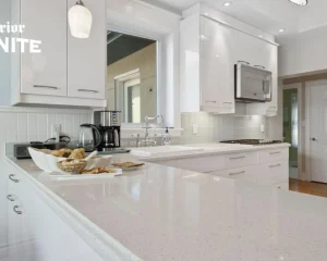 White granite kitchen countertops in a modern kitchen with white cabinets, subway tile backsplash, and built-in appliances.