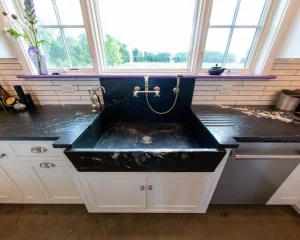 Black marble farmhouse kitchen basin integrated into custom stone sinks setup.