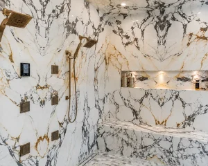 Marble-look large slab walk-in enclosure with gold fixtures: Porcelain Custom Showers.
