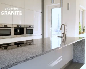 Modern white kitchen with polished stone island, showcasing custom granite countertops cost considerations for stylish and durable home upgrades.