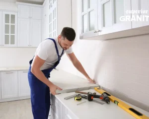 Professional installer fitting a new stone slab to help estimate Kitchen Countertop Replacement Cost.