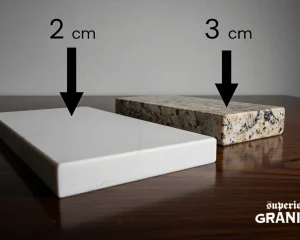 A side-by-side comparison of 2 cm vs 3 cm countertops featuring a thin white marble-style slab and a thicker, speckled granite sample.