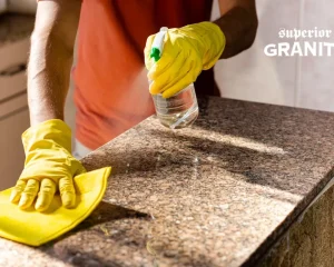 Professional using granite countertop stain removal spray to clean and restore a stone kitchen surface.
