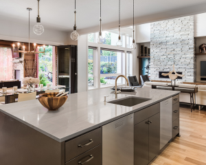 A modern white kitchen with a large granite island and wooden stools, showcasing current Kitchen Countertop Trends in Florida.