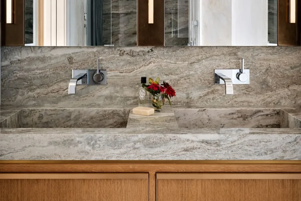 Double bathroom vanity with integrated marble basins featuring custom stone sinks.