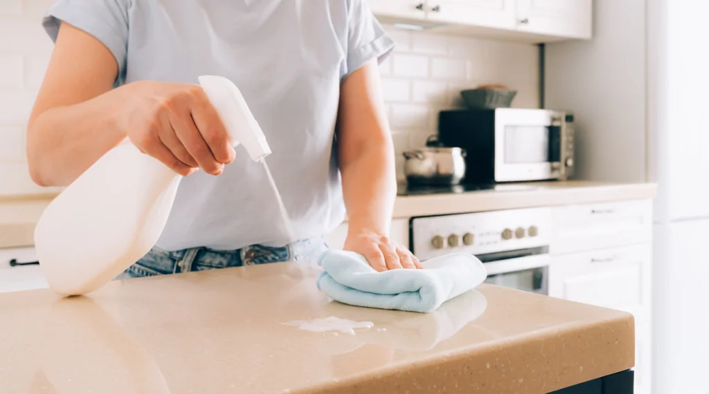 Person spraying cleaner on countertop answering Do You Need to Seal Quartz queries.