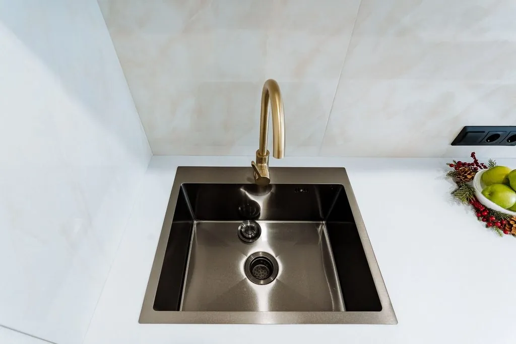 Gold high-arc faucet with dark stainless steel basin for modern Types of Kitchen Sinks.